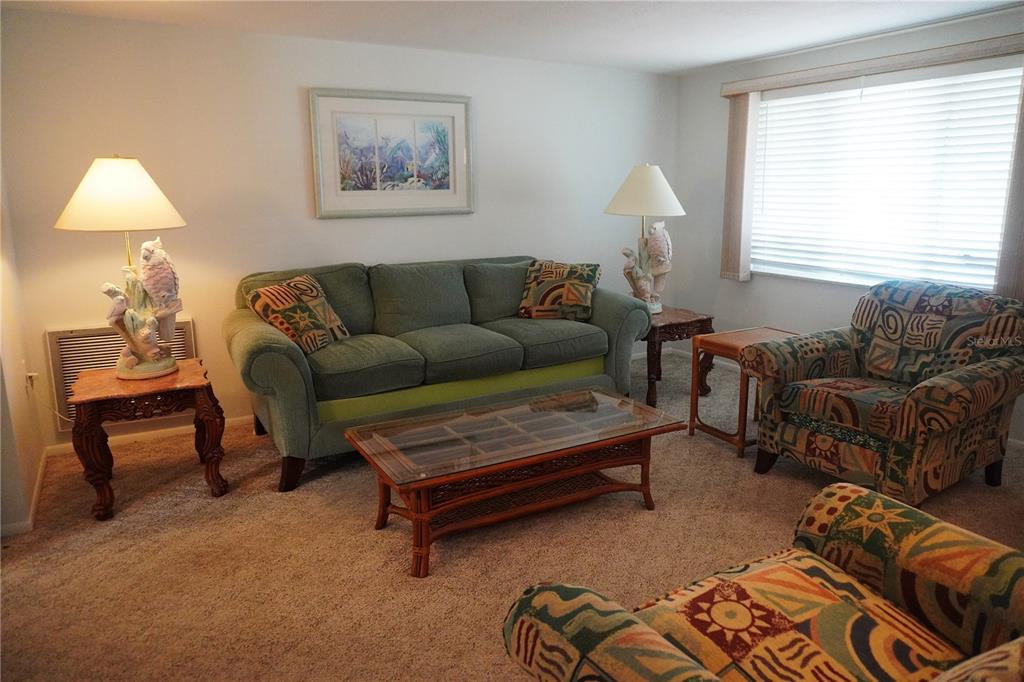 A living room features a green sofa, patterned armchairs, and a glass-topped coffee table — 1248 ERMINE DRIVE, HOLIDAY, FL