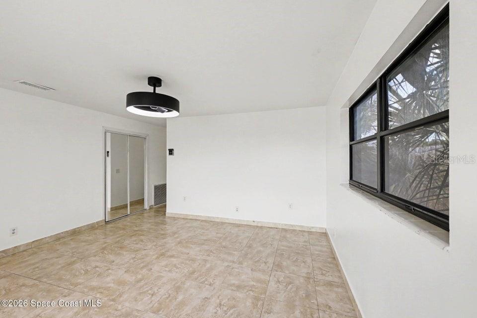 An empty room features white walls, tile flooring, a ceiling fan, and a large window — 2292 LAKEVIEW DRIVE, MELBOURNE, FL