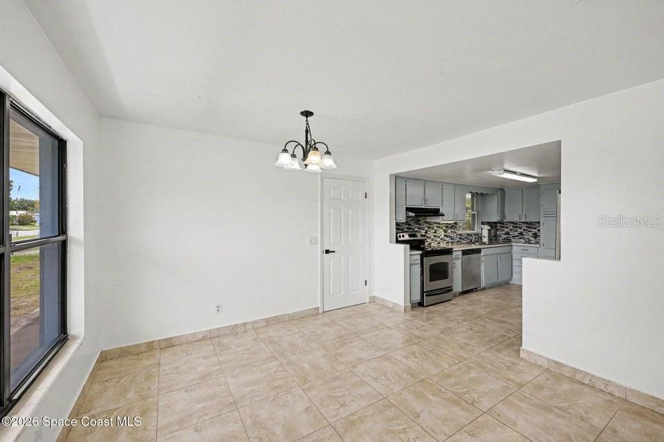 A dining area with tile flooring leads into a kitchen with light-colored cabinets — 2292 LAKEVIEW DRIVE, MELBOURNE, FL