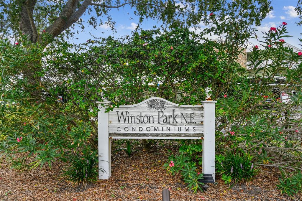 A wooden sign for Winston Park N.E. Condominiums stands in front of lush green bushes — 4885 1ST STREET NE UNIT 203, ST PETERSBURG, FL