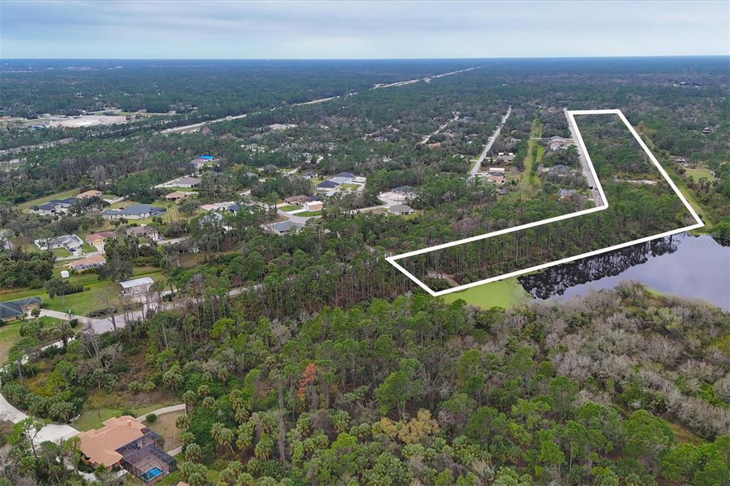 An aerial view shows a wooded lot outlined in white next to a small lake — LOT A,B,C,D,E,F NARCISSUS TERRACE, NORTH PORT, FL