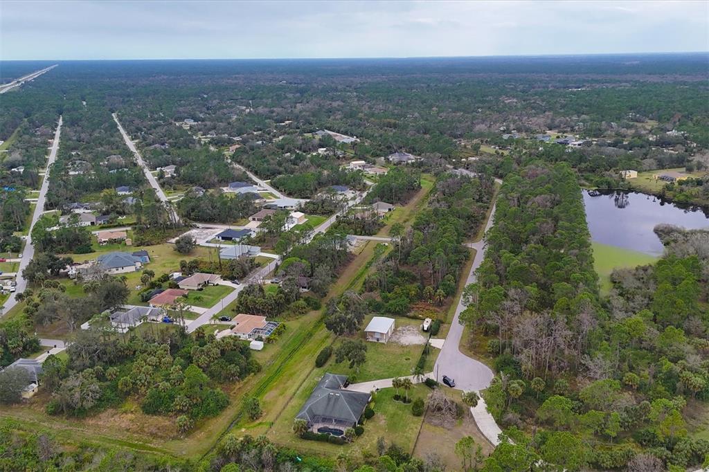 An aerial view shows a residential neighborhood with houses, wooded areas, and a small lake — LOT A,B,C,D,E,F NARCISSUS TERRACE, NORTH PORT, FL