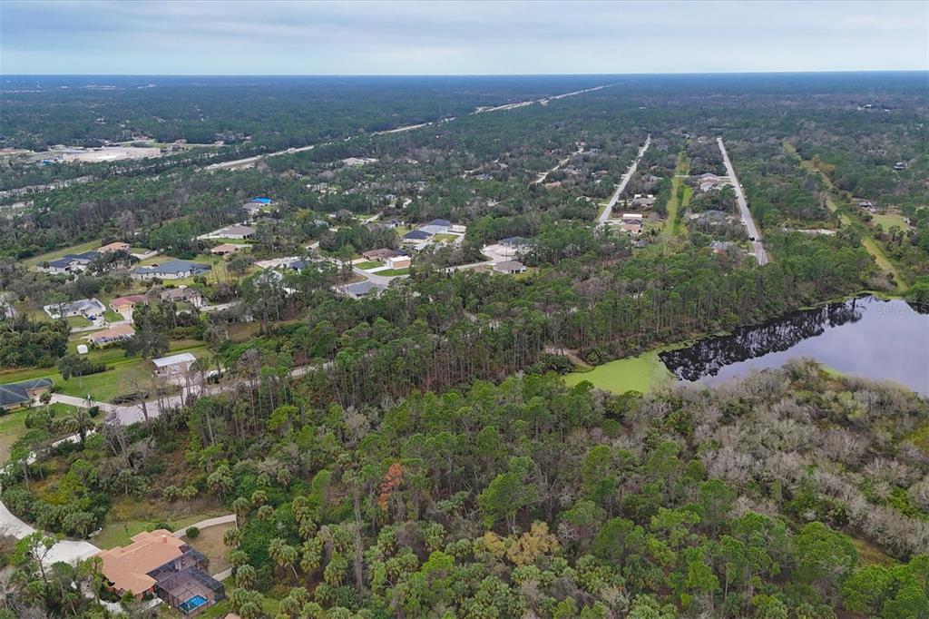 An aerial view shows a residential neighborhood with houses, dense trees, and a small lake — LOT A,B,C,D,E,F NARCISSUS TERRACE, NORTH PORT, FL