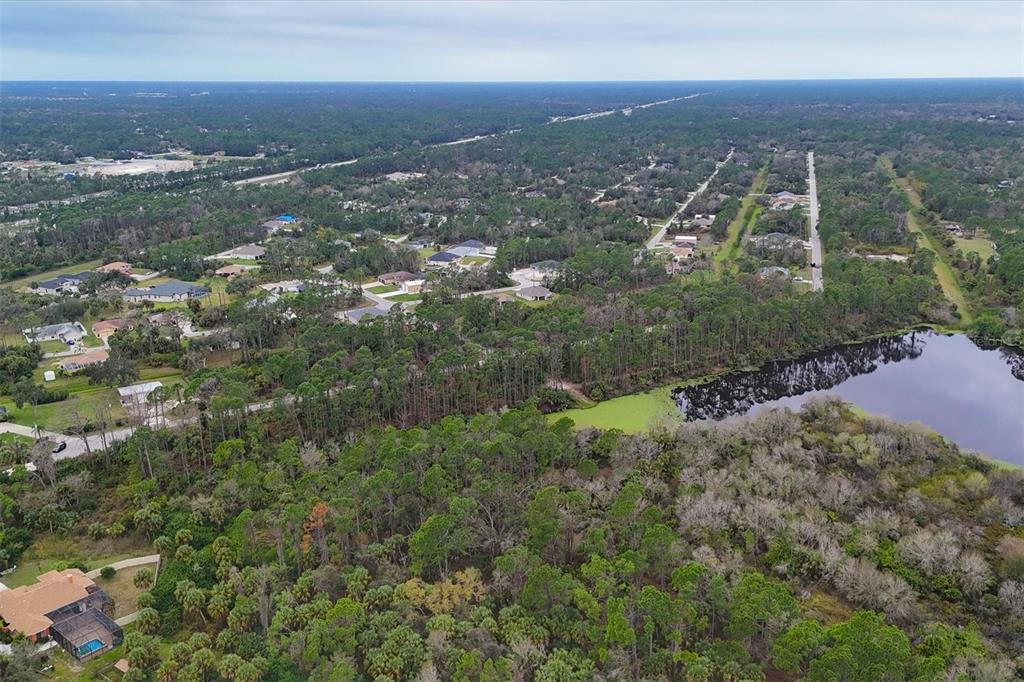 An aerial view shows a wooded residential area with a pond and scattered houses — LOT A,B,C,D,E,F NARCISSUS TERRACE, NORTH PORT, FL