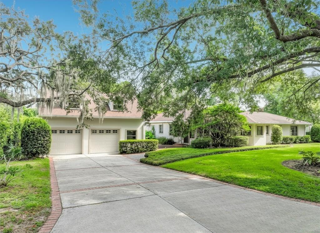 A two-story house with a two-car garage and a concrete driveway under large oak trees — 1661 LAUREL ROAD, WINTER PARK, FL