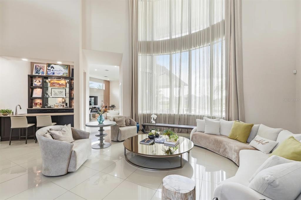 A living room features a curved sofa, a mirrored coffee table, and floor-to-ceiling windows — 3986 ISABELLA CIRCLE, WINDERMERE, FL