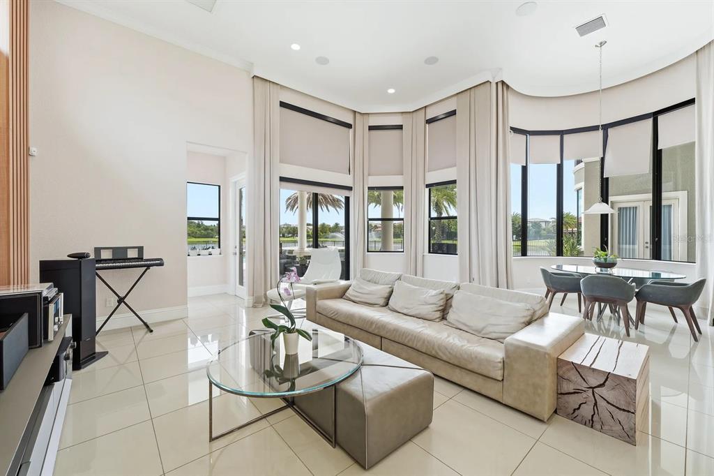 A bright living room features large windows, light tile flooring, a sofa, and dining area — 3986 ISABELLA CIRCLE, WINDERMERE, FL
