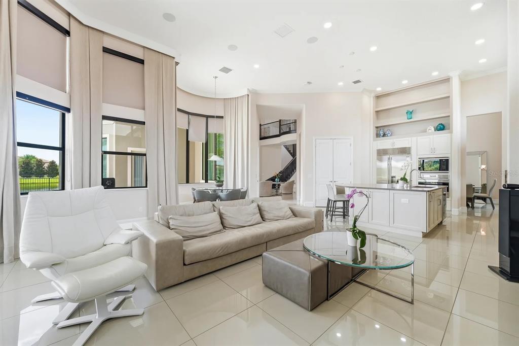 A bright, open-concept living room and kitchen featuring tile floors, high ceilings, and large windows — 3986 ISABELLA CIRCLE, WINDERMERE, FL