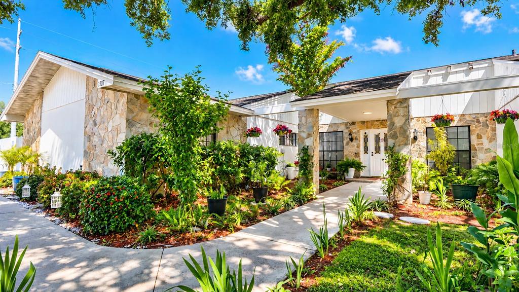 A living room features a large sectional sofa, a television, and white tile flooring — 1307 NORMANDY CIRCLE, PALM HARBOR, FL
