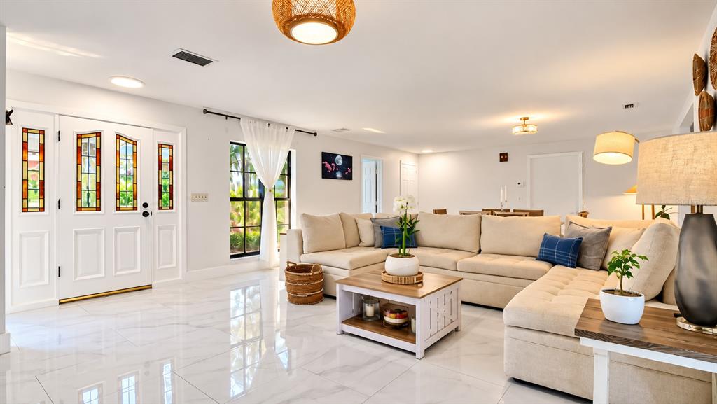 A kitchen features a large white island with wine storage, marble countertops, and tile flooring — 1307 NORMANDY CIRCLE, PALM HARBOR, FL