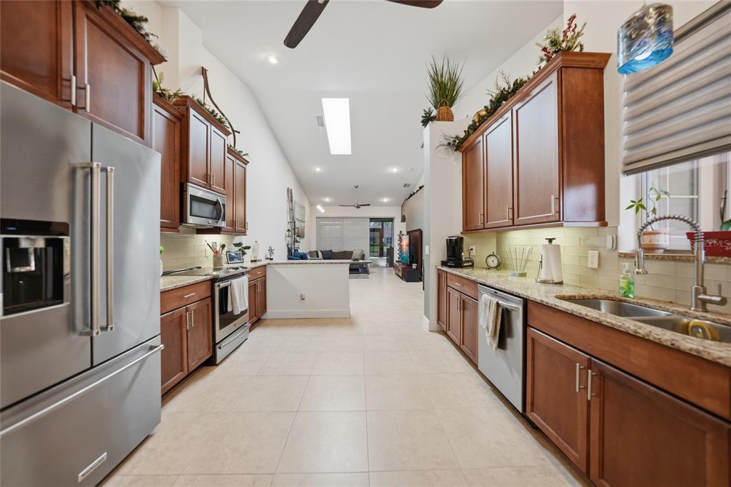 A galley kitchen features wood cabinets, stainless steel appliances, and tile flooring — 4691 TURNBERRY CIRCLE, NORTH PORT, FL