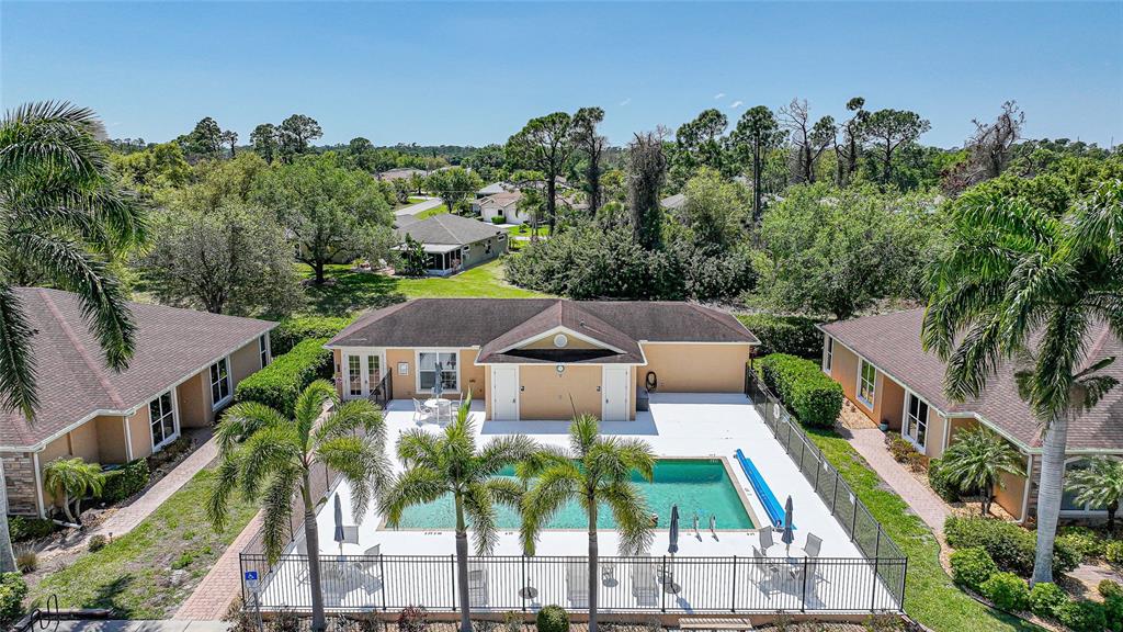 An aerial view shows a community swimming pool surrounded by a fence and palm trees — 4691 TURNBERRY CIRCLE, NORTH PORT, FL