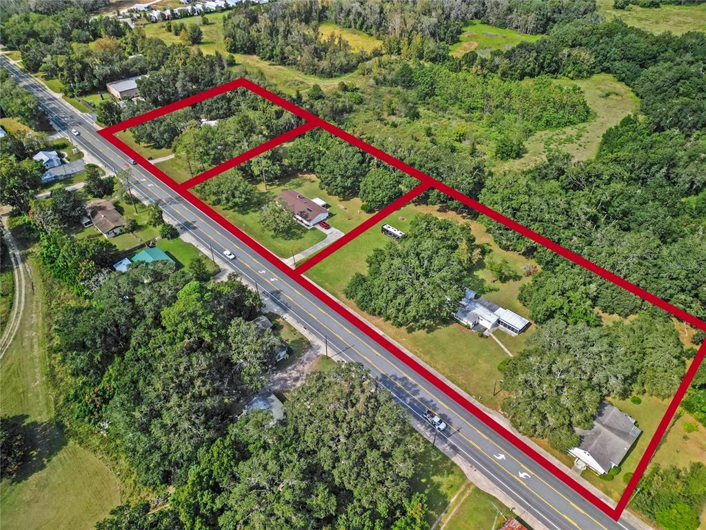 An aerial view shows three adjacent residential lots outlined in red along a paved road — 3696 E C-466, OXFORD, FL