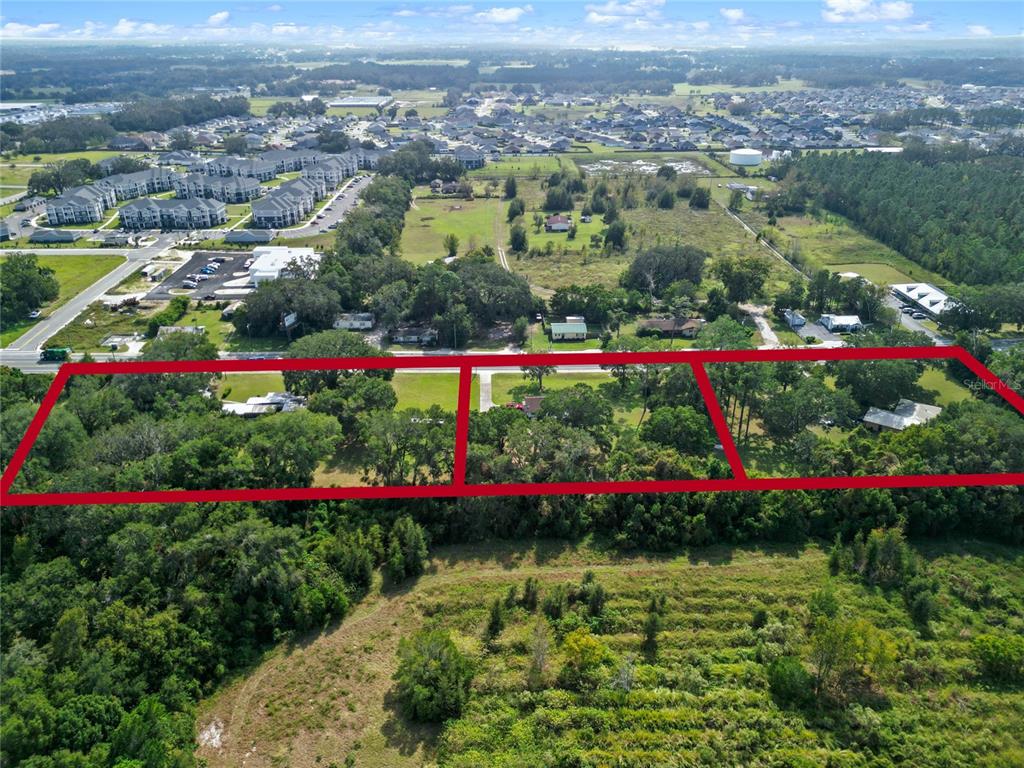 An aerial view shows three adjacent wooded residential lots outlined in red along a road — 3696 E C-466, OXFORD, FL