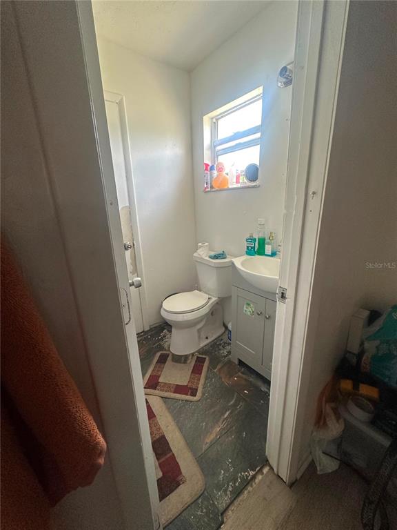 A small bathroom features a white toilet, a grey vanity sink, and dark tiled flooring — 1838 SW HARLEM CIRCLE, ARCADIA, FL