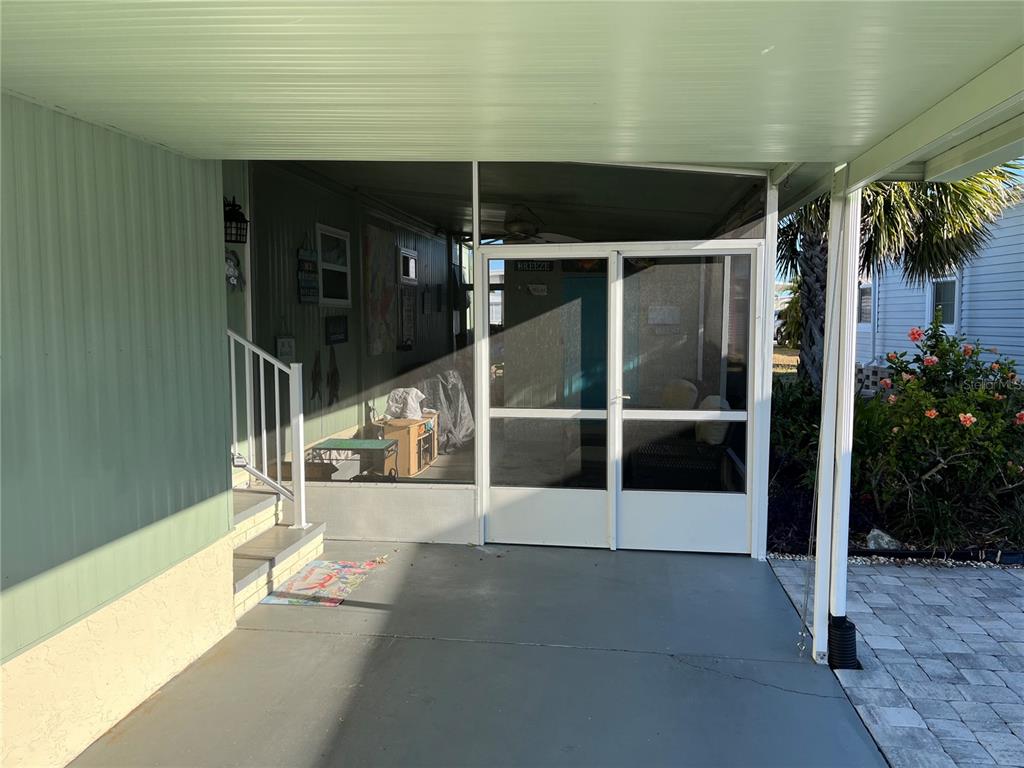 A covered carport leads to a screened-in porch with stairs and a white door — 712 ROMA ROAD, VENICE, FL