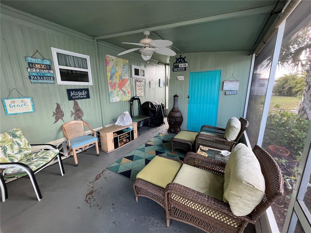 A screened-in porch features wicker furniture, a ceiling fan, and light green paneled walls — 712 ROMA ROAD, VENICE, FL