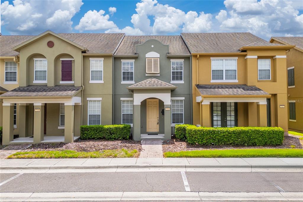 A row of three attached townhomes with tan, green, and yellow stucco facades — 7723 FAIRGROVE AVENUE, WINDERMERE, FL