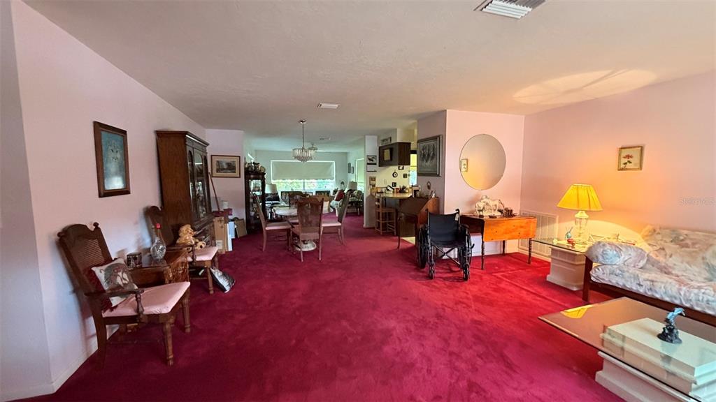 A living and dining area features red carpeting, light pink walls, and traditional wooden furniture — 212 S LUCILLE STREET, BEVERLY HILLS, FL
