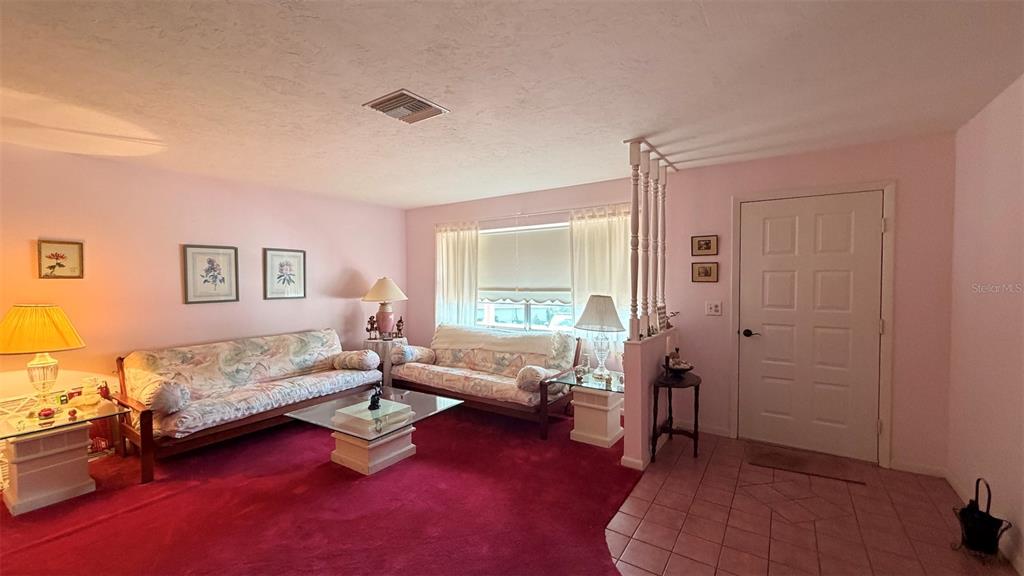 A living room features pink walls, red carpeting, two sofas, and a white front door — 212 S LUCILLE STREET, BEVERLY HILLS, FL