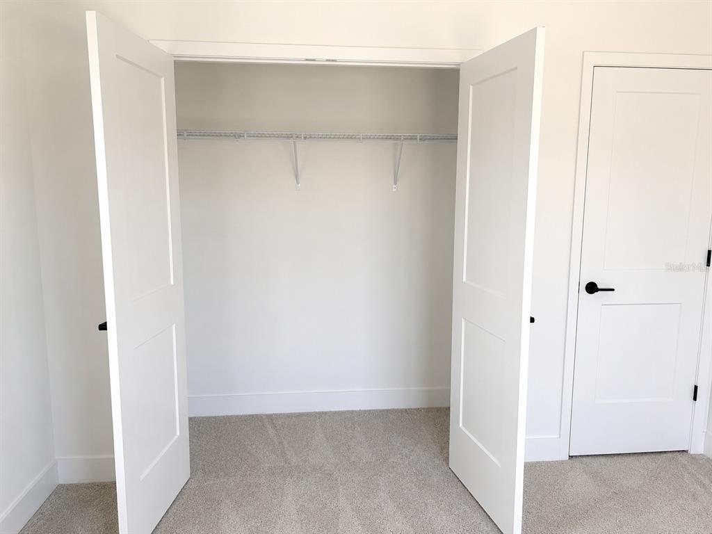A closet with white double doors and a wire shelf stands next to a bedroom door — 1680 ANN ROSE WAY, LEESBURG, FL