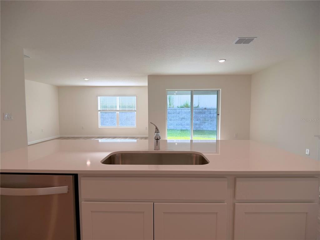 A kitchen island with a stainless steel sink faces a living area with sliding doors — 7230 SE 112TH LANE, BELLEVIEW, FL