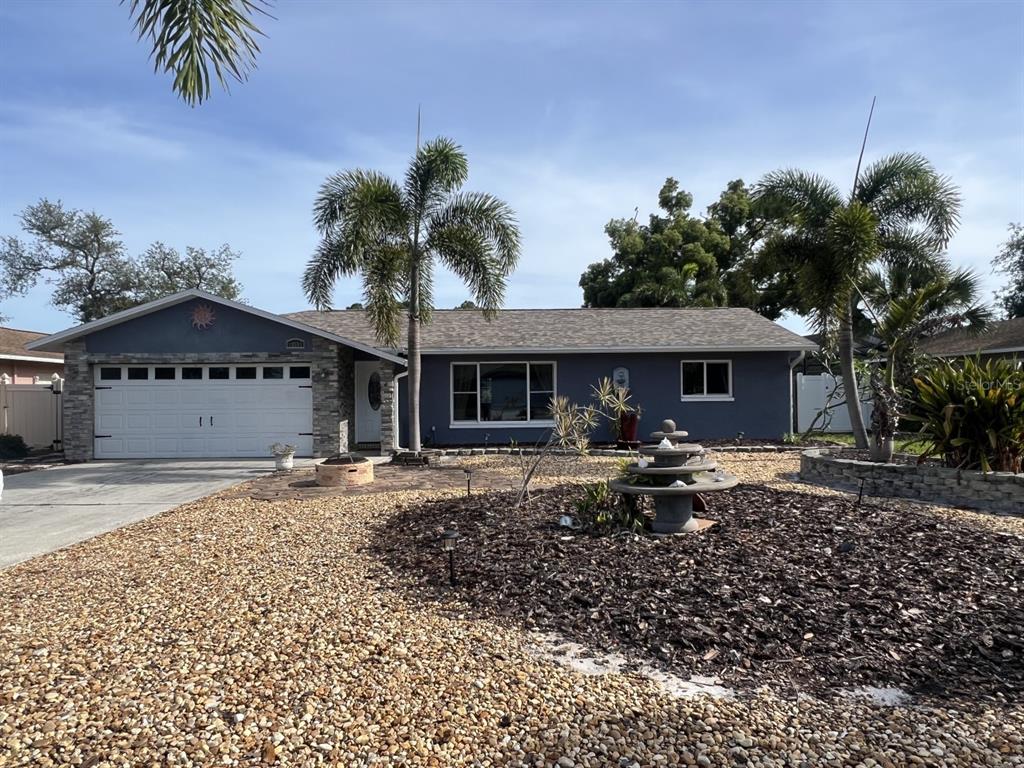 A single-story house with a gray exterior, a white garage door, and a landscaped front yard — 12341 79TH PLACE, SEMINOLE, FL