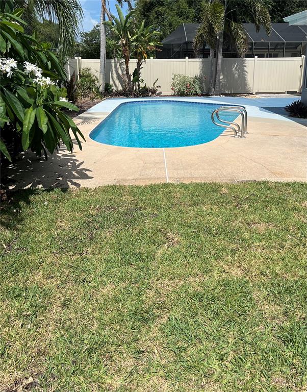 A backyard features a swimming pool with metal handrails, a tan deck, and a privacy fence — 12341 79TH PLACE, SEMINOLE, FL