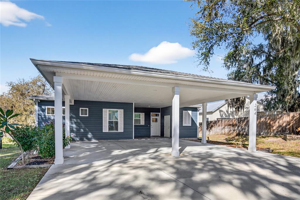 A blue house exterior features a large concrete carport with white support columns — 260 S CENTRAL AVENUE, UMATILLA, FL