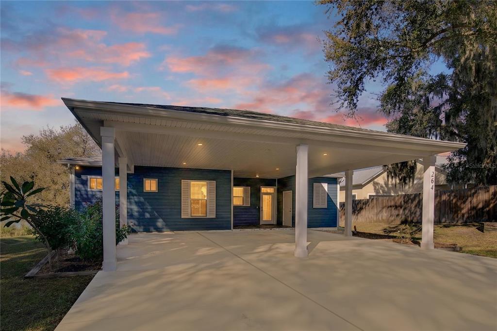 A blue house exterior features a large covered carport with white columns and concrete flooring — 260 S CENTRAL AVENUE, UMATILLA, FL