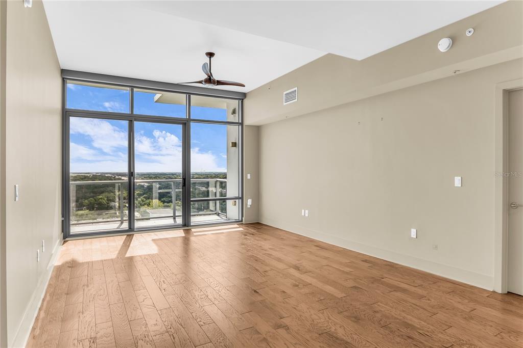 An empty room with hardwood floors, a ceiling fan, and large windows leading to a balcony — 260 S OSCEOLA AVENUE UNIT 1602, ORLANDO, FL