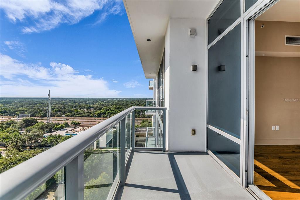 A high-rise balcony with a glass railing overlooks a highway and a forested landscape — 260 S OSCEOLA AVENUE UNIT 1602, ORLANDO, FL