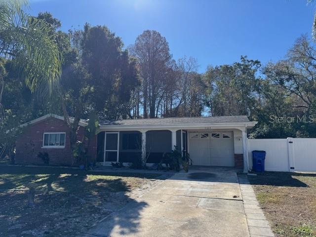 A single-story brick house with a white fence and palm trees in the front yard — 7235 REDBUD COURT, NEW PORT RICHEY, FL