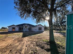 A light-colored single-story house with a two-car garage and a large tree in front — 37041 HIDDEN VIEW CIRCLE, DADE CITY, FL