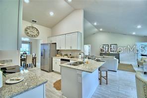 An open-concept living room features a beige sectional sofa, a round ottoman, and tile flooring — 37041 HIDDEN VIEW CIRCLE, DADE CITY, FL