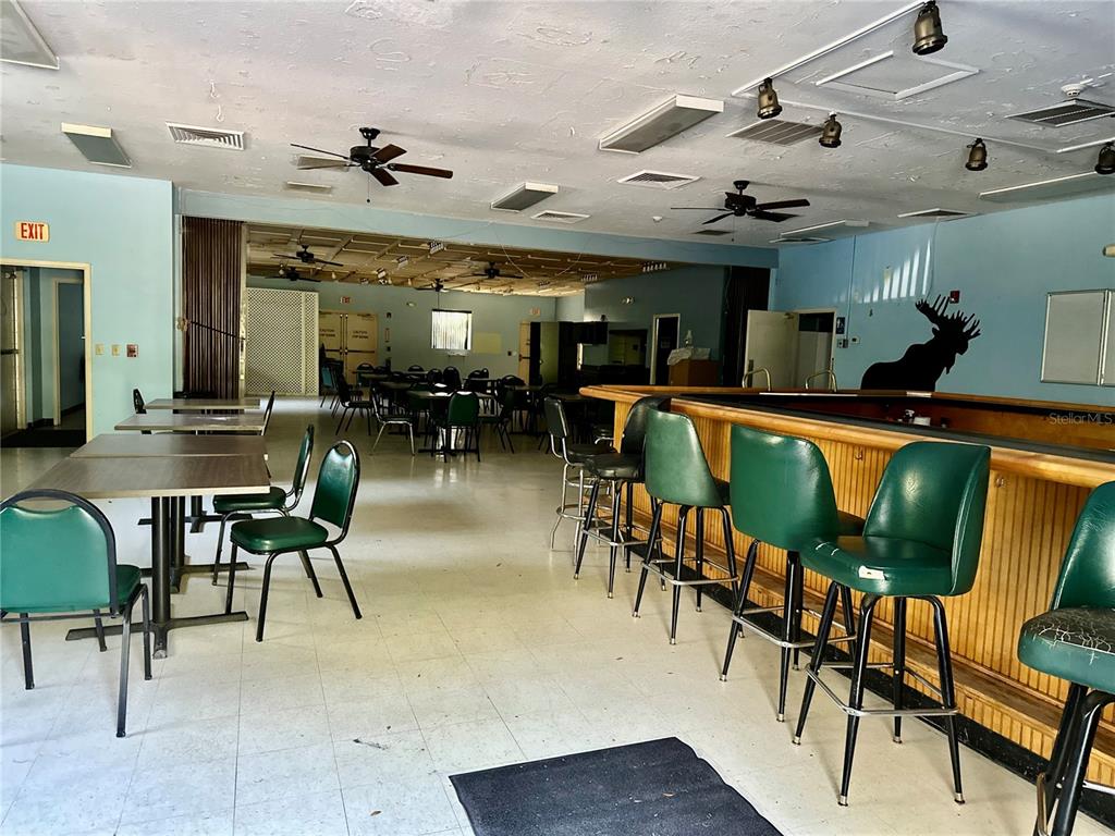 A commercial bar area features green stools, tables, and a moose silhouette on the wall — 54750 COUNTY ROAD 445A, ASTOR, FL