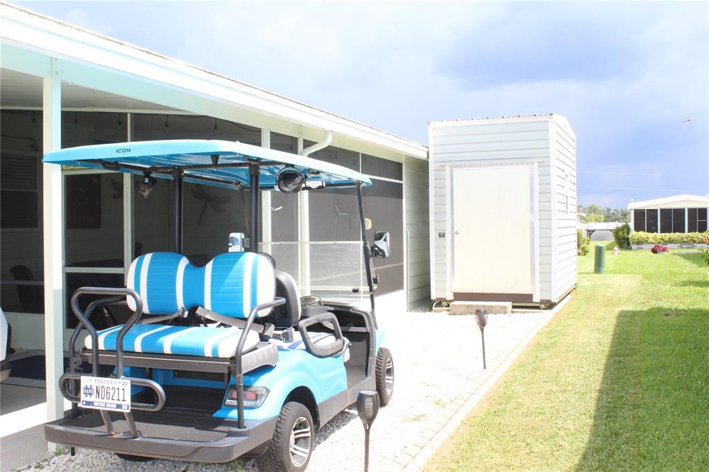 A blue and white golf cart is parked on a gravel driveway beside a house — 4415 14TH STREET E, ELLENTON, FL