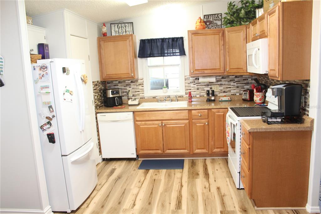 A kitchen with wood cabinets, light countertops, a white refrigerator, and wood-look flooring — 4415 14TH STREET E, ELLENTON, FL