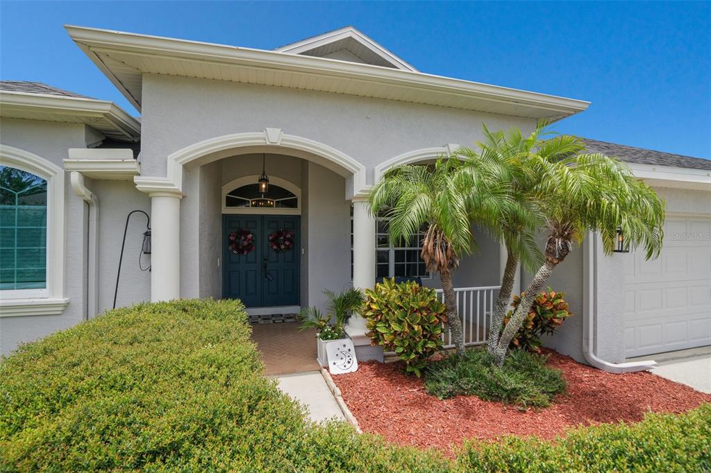 The exterior of a gray house features a covered entryway with columns and a palm tree — 2117 LARKSPUR COURT, TRINITY, FL