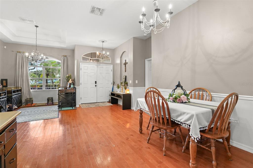 A dining room with hardwood floors, a chandelier, and a table set for four — 2117 LARKSPUR COURT, TRINITY, FL
