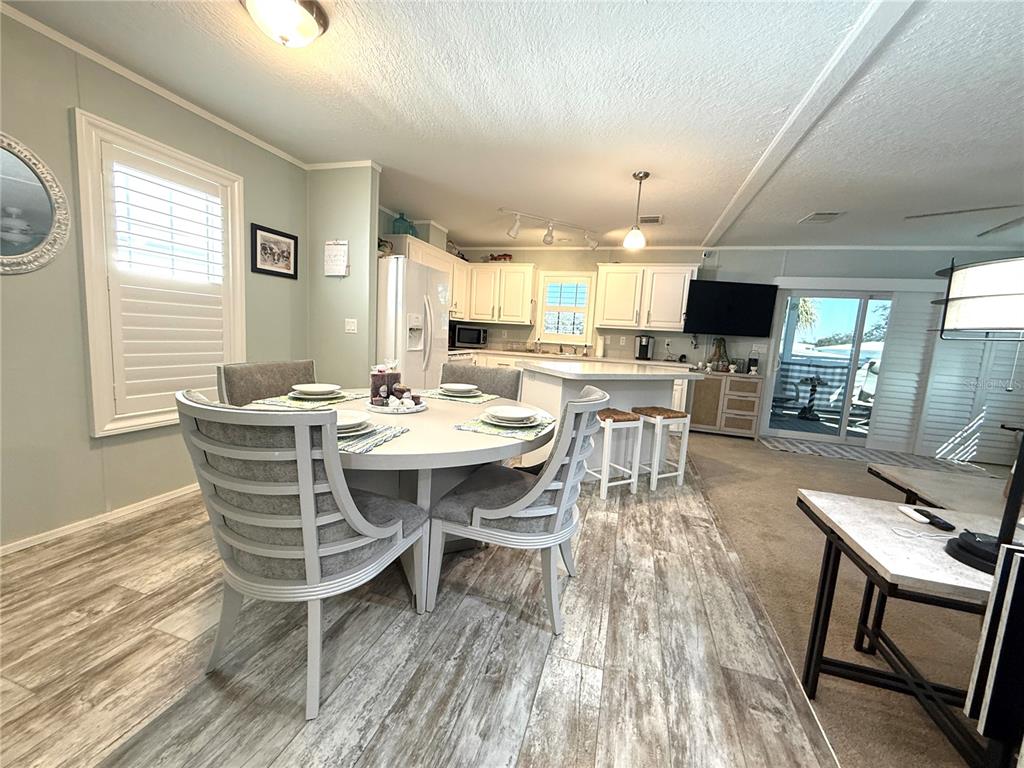 A dining area with a round table and chairs sits adjacent to a white kitchen — 124 E SAINT ANNES CIRCLE, APOLLO BEACH, FL