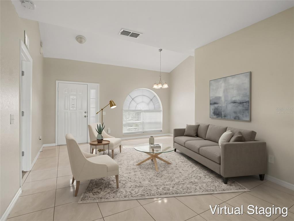 A bright room with beige tile flooring, a vaulted ceiling, and an arched window — 1802 HUDSON COURT, KISSIMMEE, FL