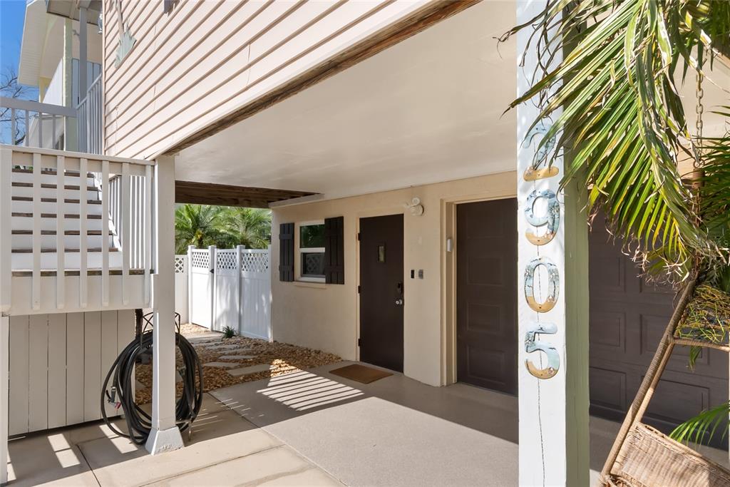 A ground-level covered patio area features a brown door, a window, and a white fence — 2905 AVENUE C, HOLMES BEACH, FL