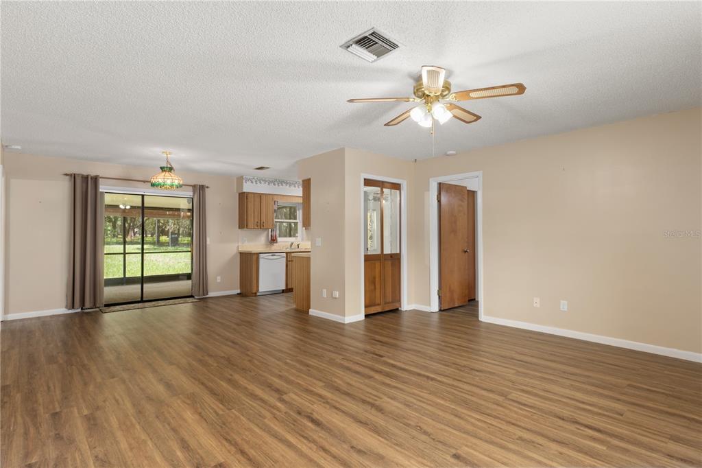 An open-concept living area features wood-look flooring, a ceiling fan, and an adjacent kitchen — 9390 E WINDWOOD LOOP, INVERNESS, FL