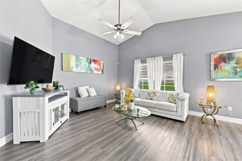 A living room features gray walls, wood-look flooring, a white media console, and a sofa — 510 CASTLEMAIN CIRCLE, DAVENPORT, FL