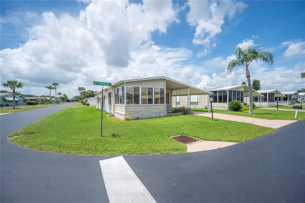 A single-story mobile home with a sunroom and carport sits on a corner lot — 95 PARSON DRIVE, WINTER HAVEN, FL