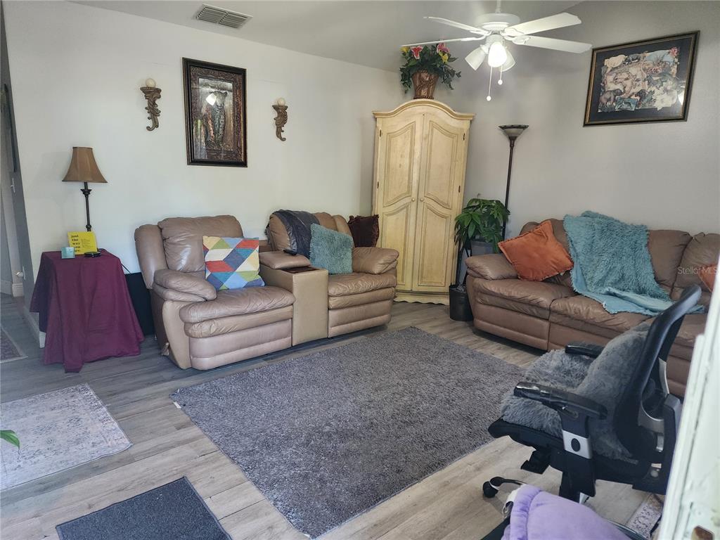 A living room features light wood-look flooring, two brown leather sofas, and a tall cabinet — 4154 16TH STREET E UNIT 15, ELLENTON, FL