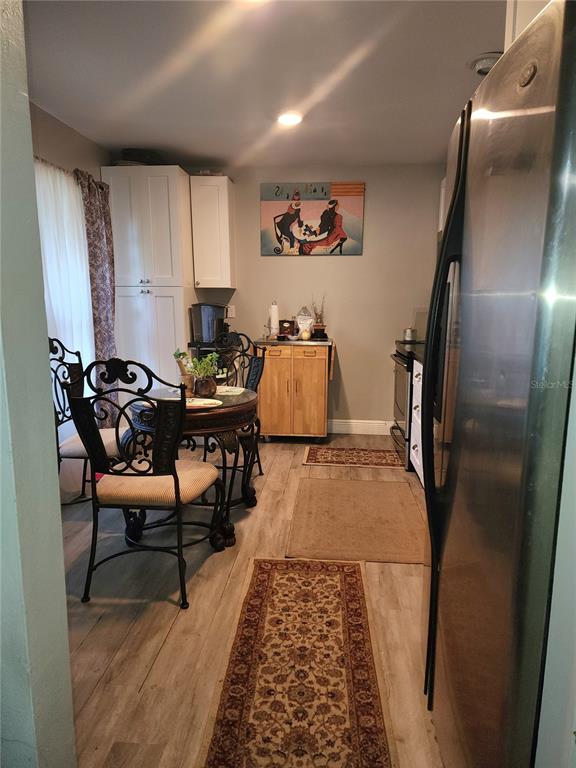 A kitchen and dining area with light wood-look flooring, a round table, and stainless steel refrigerator — 4154 16TH STREET E UNIT 15, ELLENTON, FL