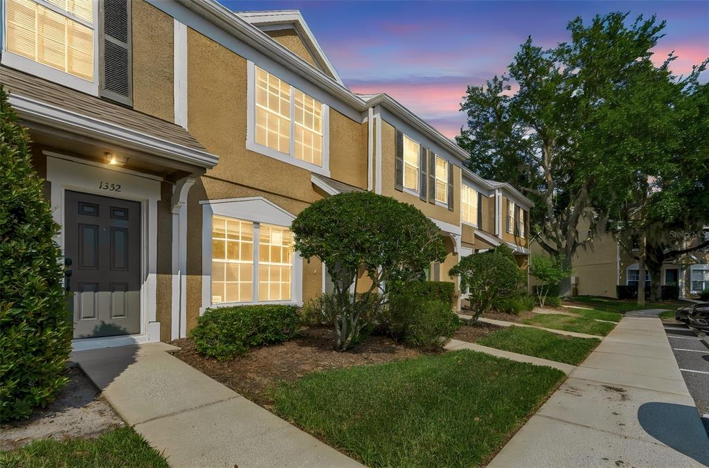 A two-story tan townhouse with a gray front door and a sidewalk at sunset — 1330 STANDRIDGE DRIVE, WESLEY CHAPEL, FL