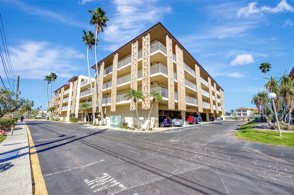 A multi-story apartment building exterior features a central glass entrance and open-air balconies — 113 ISLAND WAY UNIT 241, CLEARWATER BEACH, FL